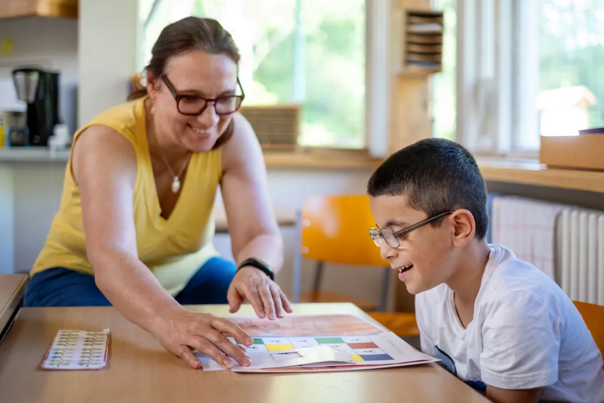 Lehrerin hilft Sch&uuml;ler beim Lesenlernen