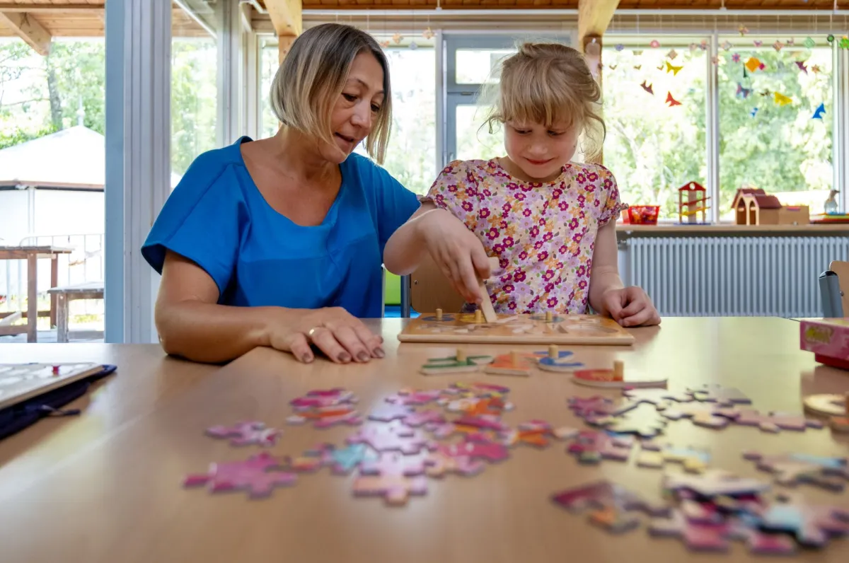 Betreuerin hilft Schülerin beim Puzzlen