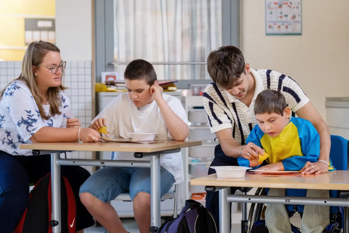 Zwei Schulbegleitungen helfen zwei Sch&uuml;lern beim Basteln